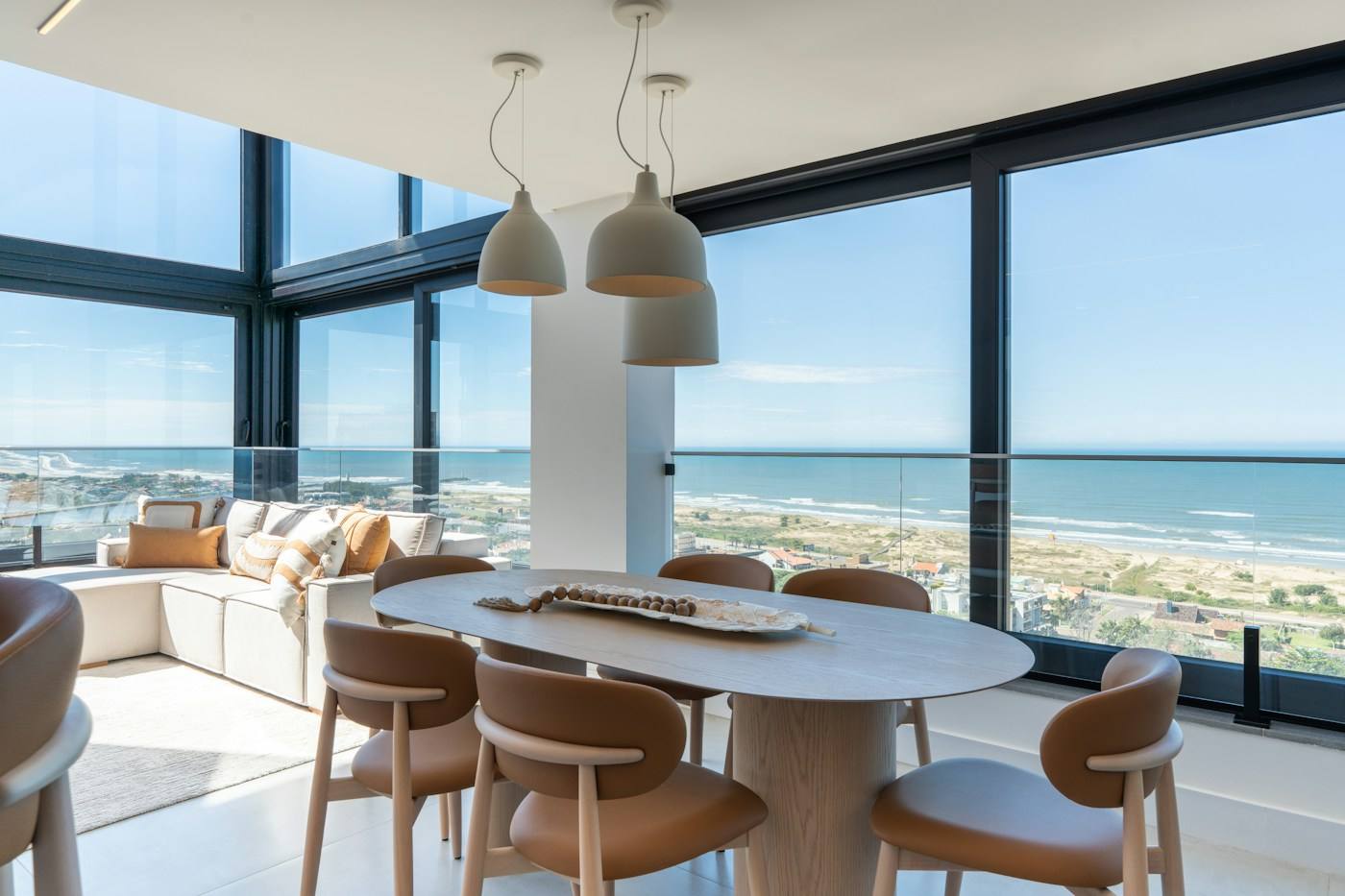 Sala de jantar com janelas do piso ao teto e vista para a praia e o mar.